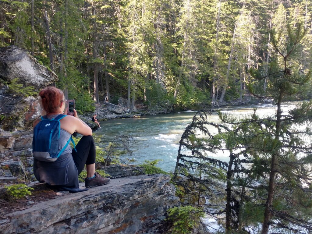 A woman with her back to the camera looking at McDonald Falls in Glacier National Park