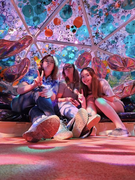 Three girls holding up peace signs inside a colorful dome