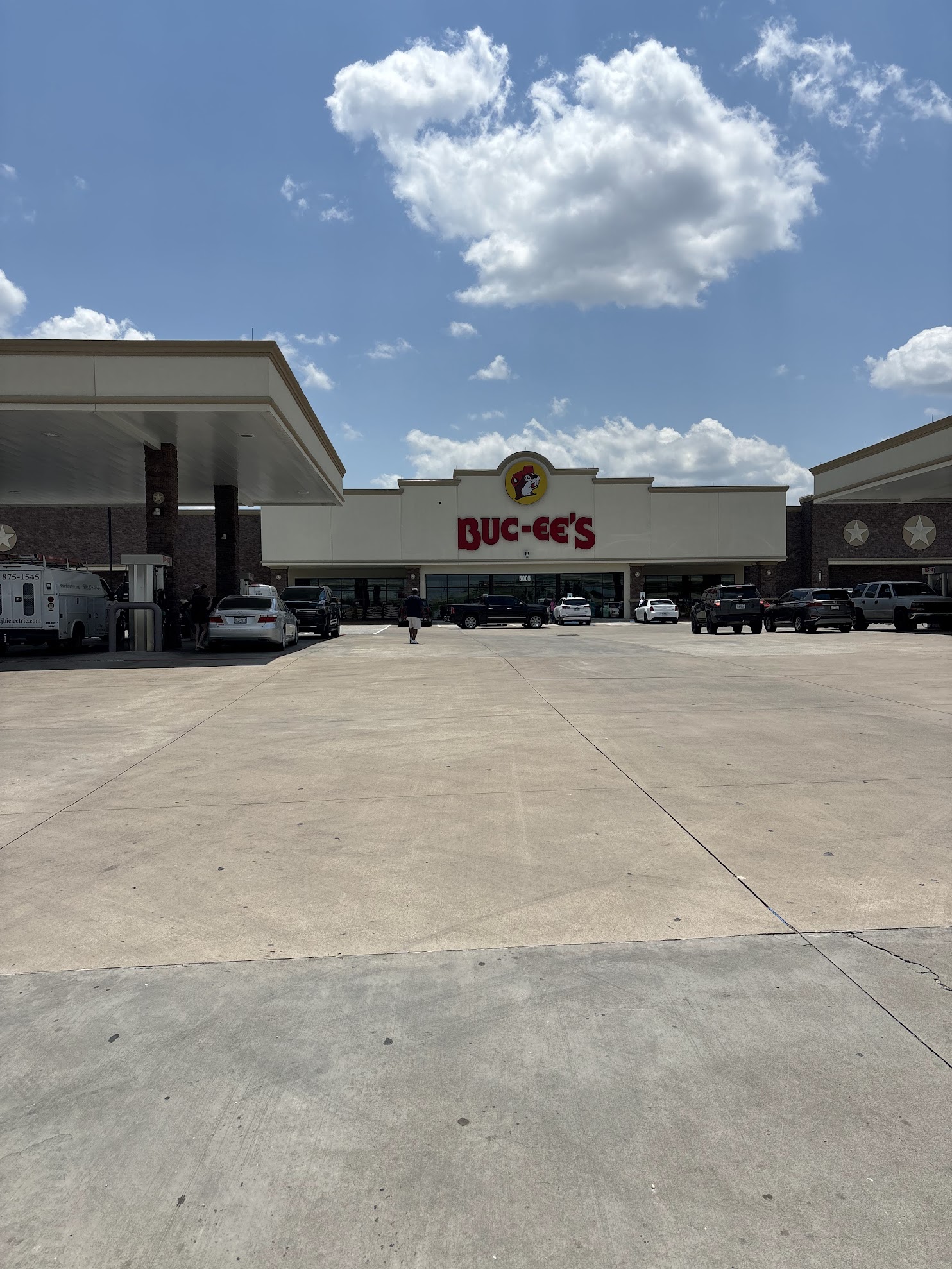 A buc-ees sign in front of a blue sky with a big cloud