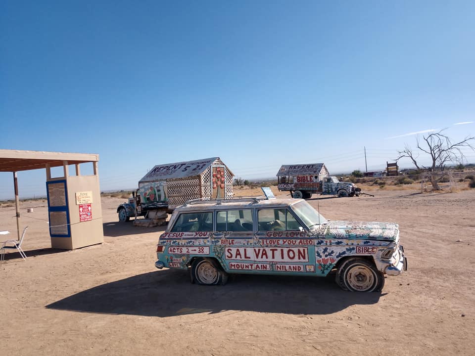 A blue car with spray paint on it found at Salvation Mountain