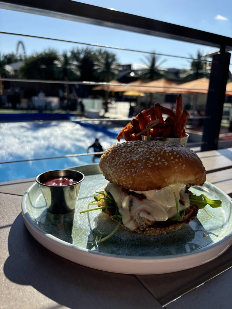 The Maui Wowie burger overlooking a female surfing a wave simulator