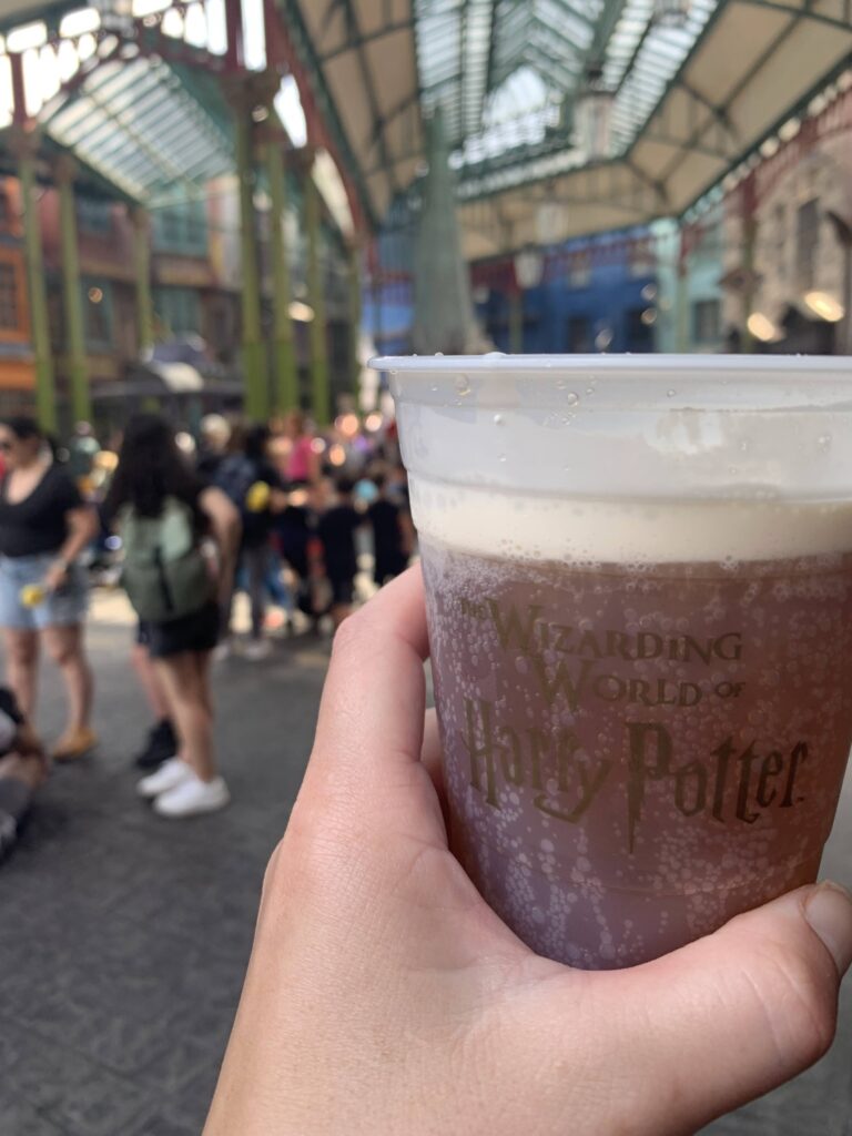 A hand holding a butter beer in Diagon Alley- Universal Studios, Florida