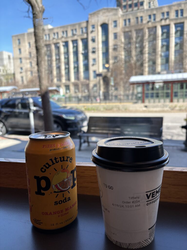 An orange soda pop can and coffee cup from Pavement Coffee