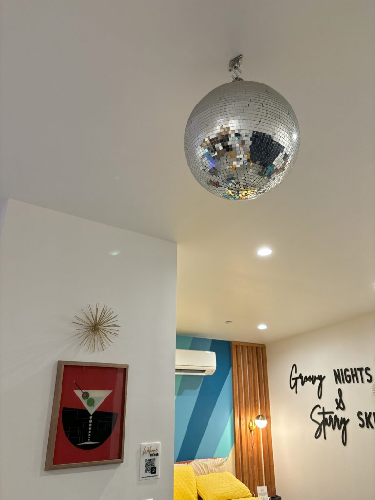 A disco ball hanging from the ceiling and colorful walls behind it