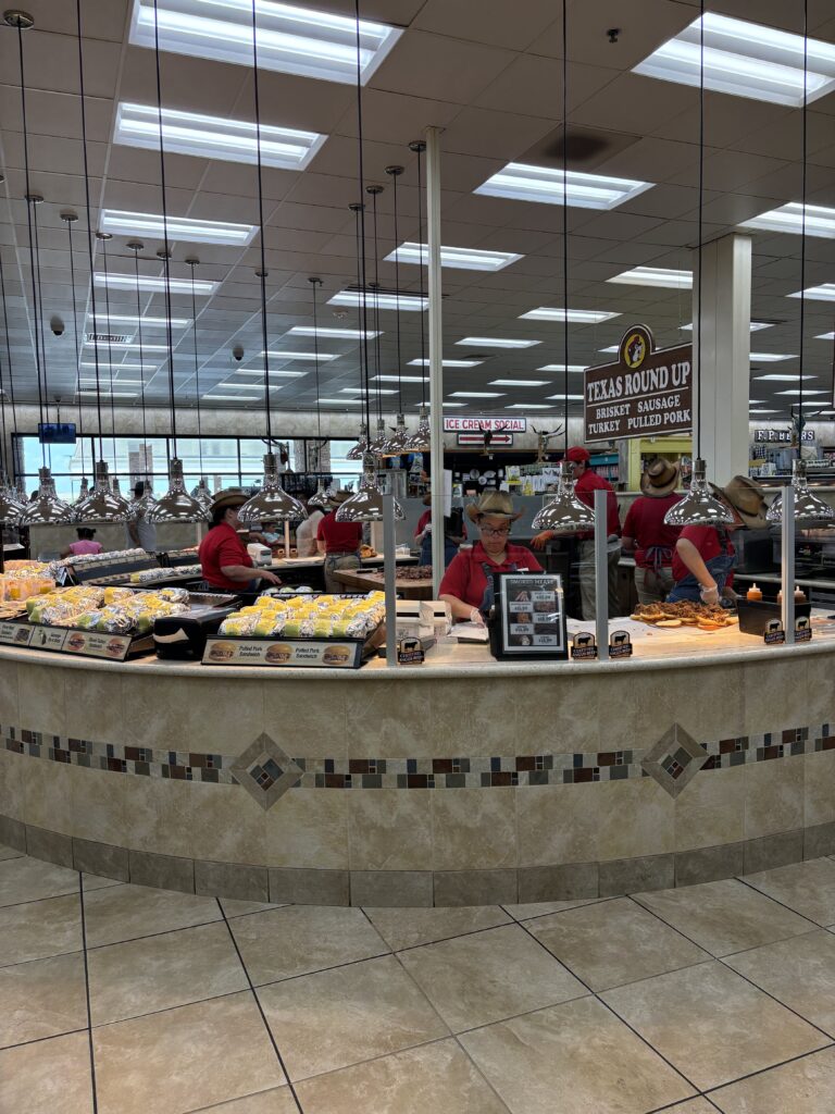 A group of people in red shirts standing around a circle cooking bbq