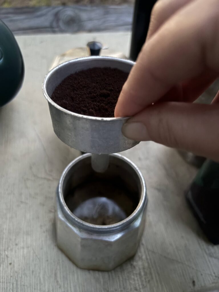 Someone holding up a middle of the moka pot with the bottom right below