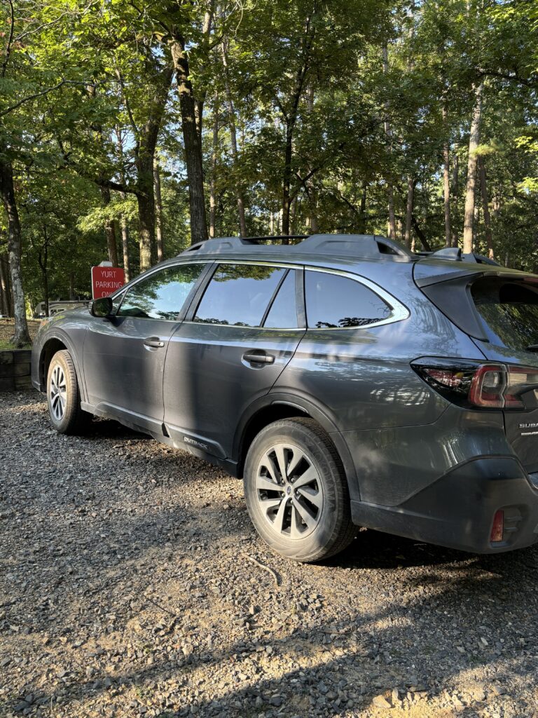 A grey Subaru Outback sitting in front of a Yurt Parking sign