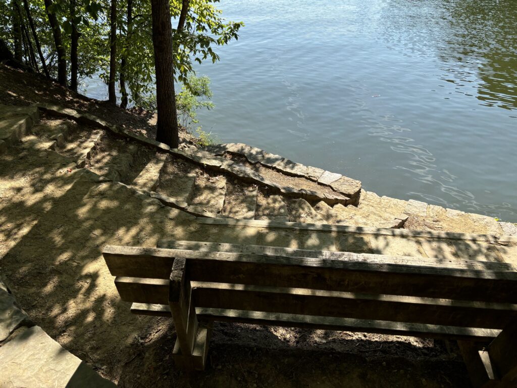 A bench with steps into a lake