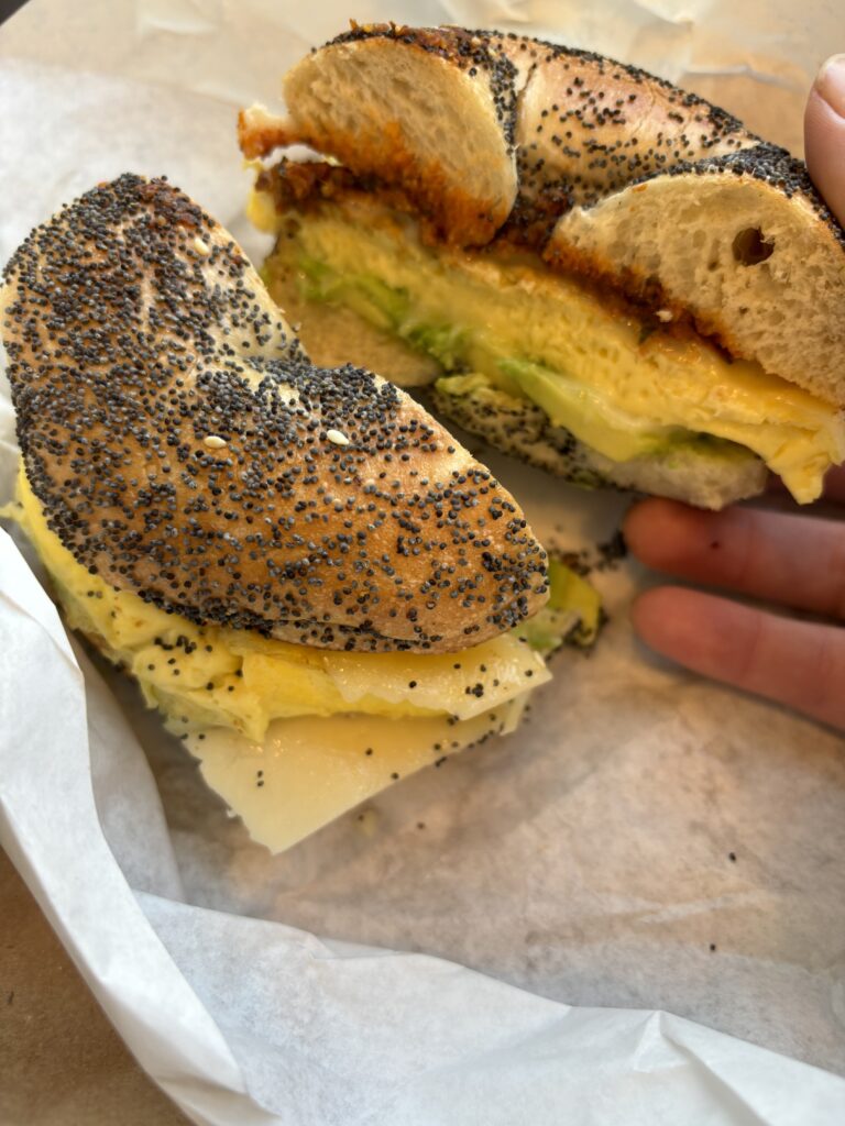 An everything bagel with eggs, avocado slices, and tomato pesto