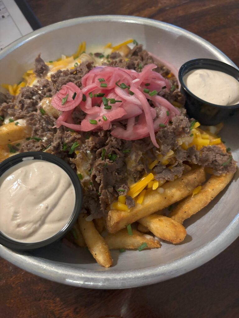 Big fries with steak, cheese, and pickled onions on top