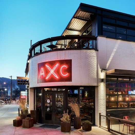 A white building with black accents and Red Neon Letters that say "AXC"