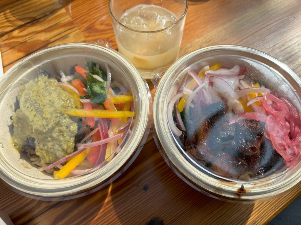 Two rice bowls on a wooden table with a drink between them