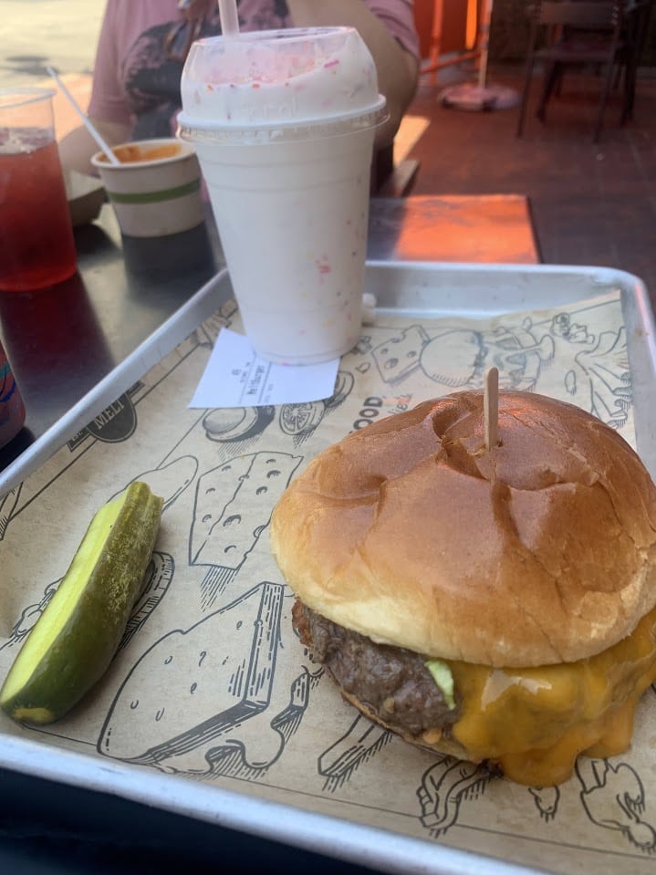  A burger with a pickle spear and a milkshake