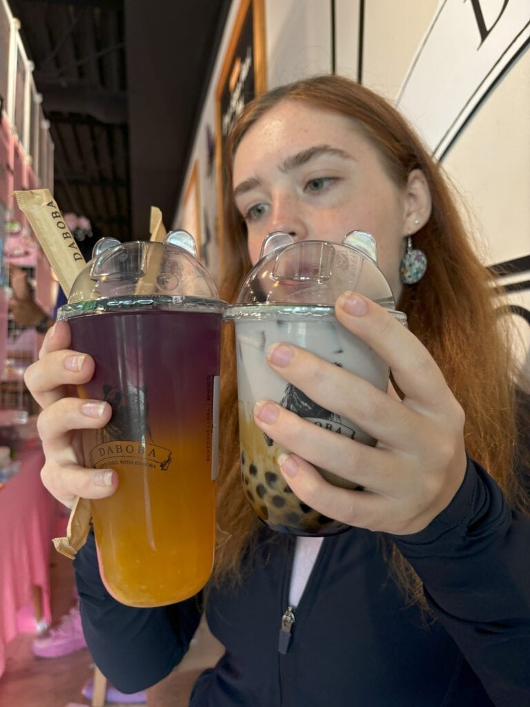 A girl holding two drinks 