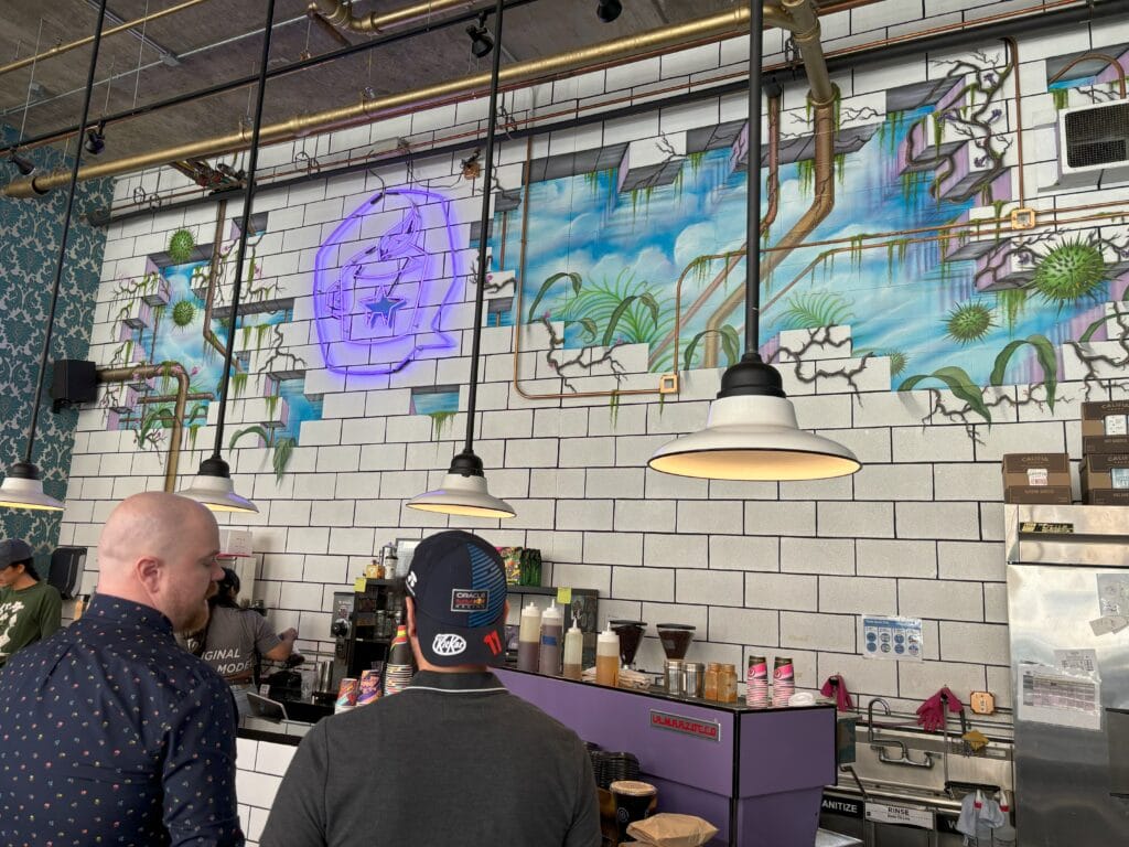 A colorful wall with a purple espresso machine in front of it