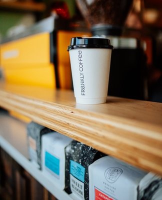 Frankly Coffee cup with yellow espresso machine in the background