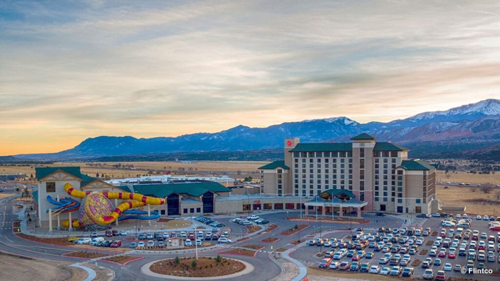 Great Wolf Lodge Building with water slides coming out of it and mountains in the background