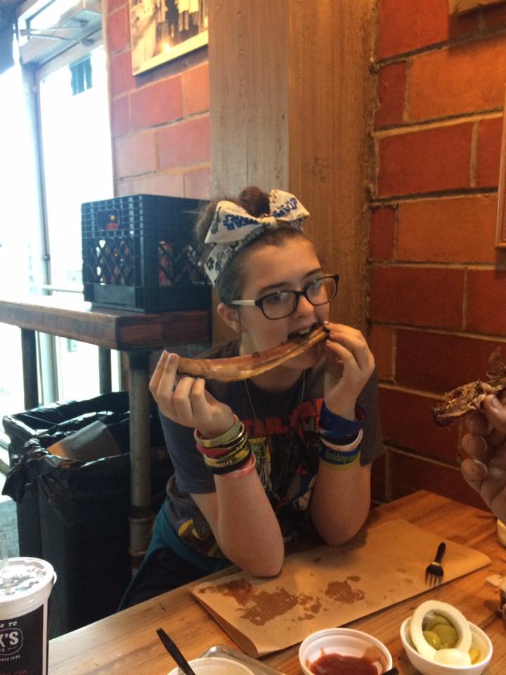 A girl Gnawing on a bone in Blacks BBQ Austin