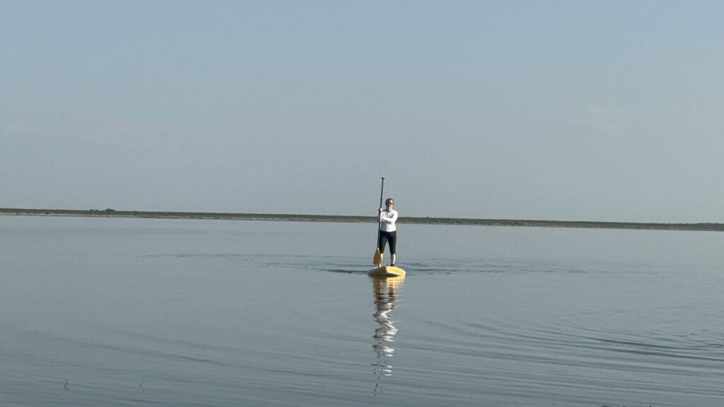 A woman standing on a stand-up paddle board in a lake