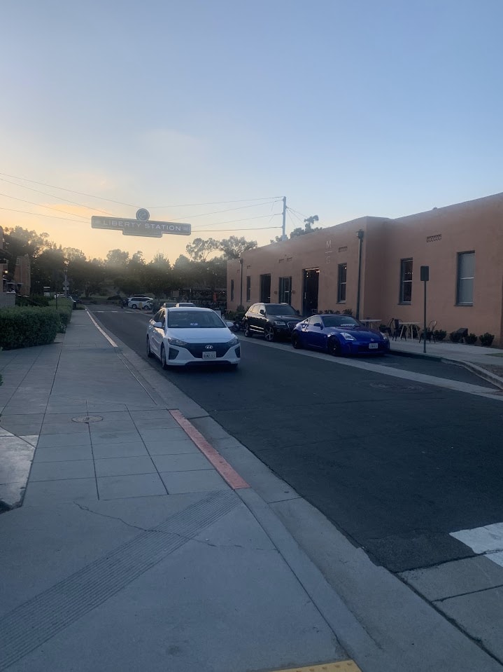 A couple of cars and a building with a sign hanging over the street that says "Liberty Square"