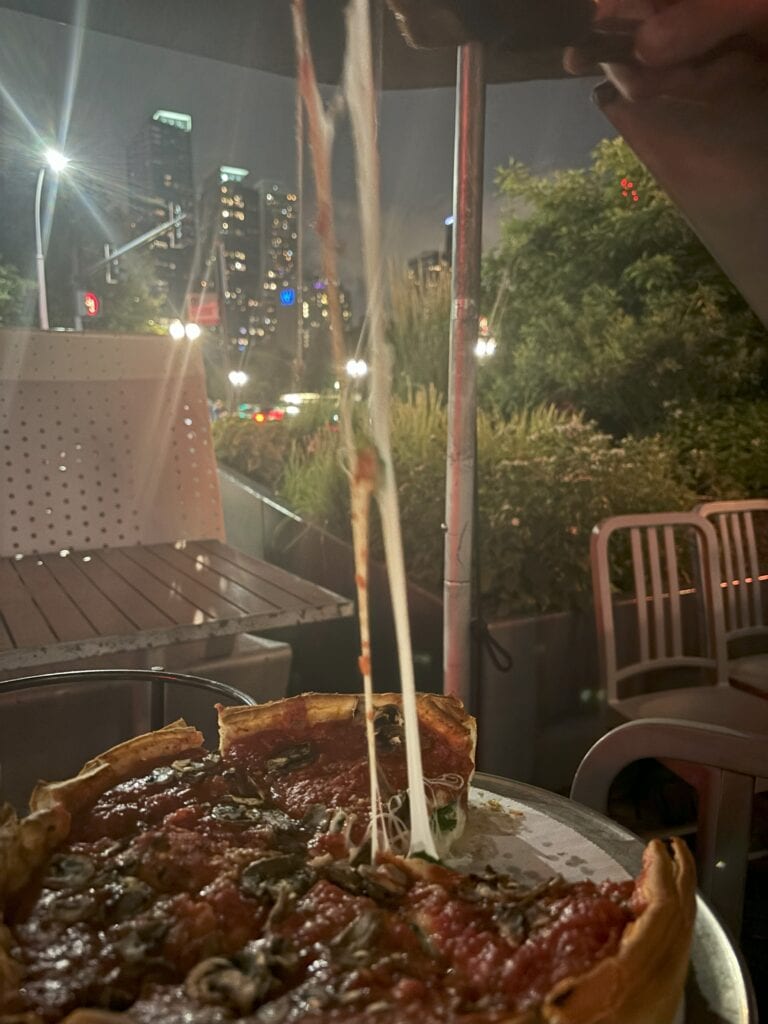 A string of cheese coming off a deep dish pizza with downtown chicago in between