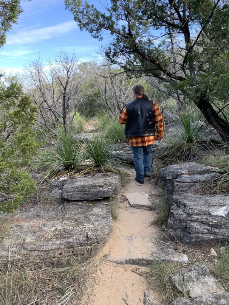 A man in a motorcycle outfit walking in the woods during the winter months