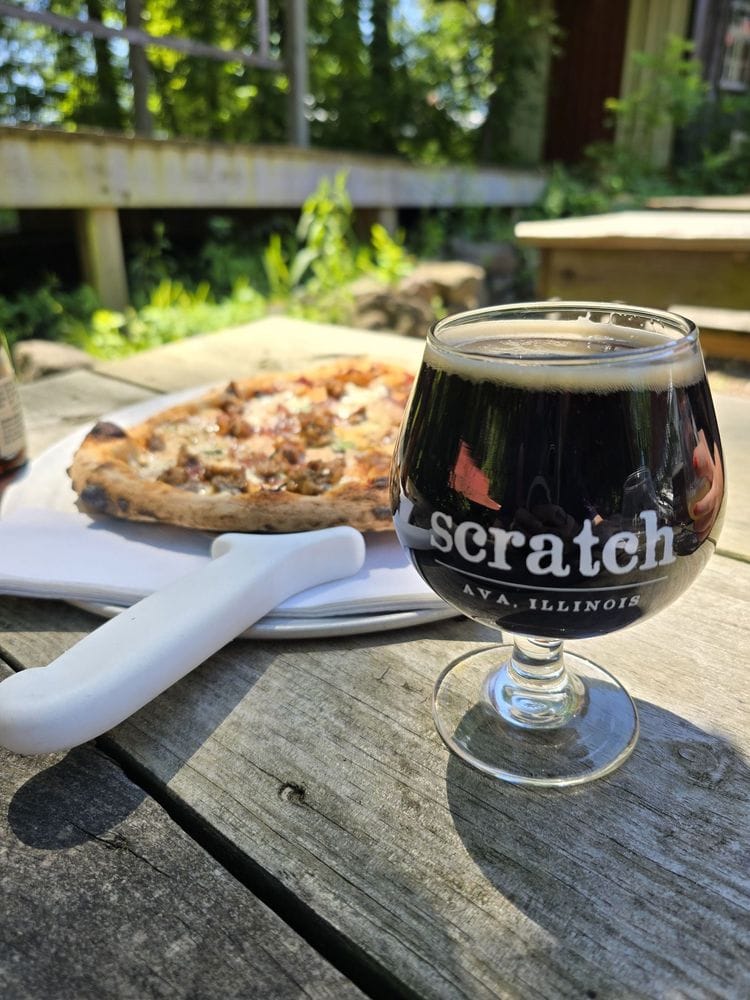 Wood-fired pizza with a beer in front of it