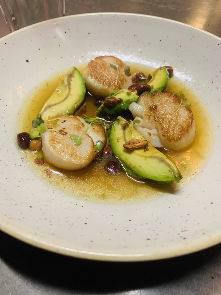 A plate with scallops, avocados, and a sauce at Supper in San Antonio