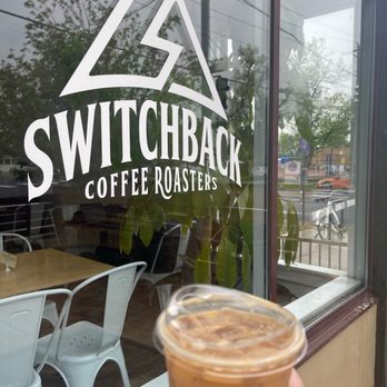 Switchback Coffee Roasters sign on a window with iced coffee in the foreground