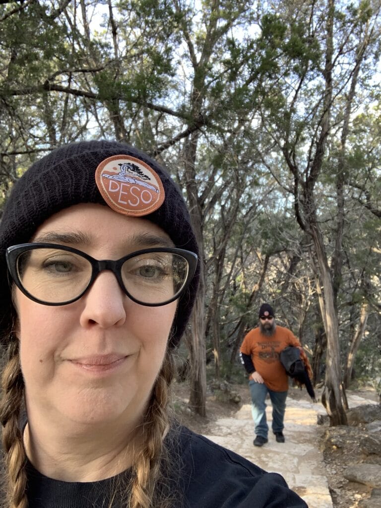 A woman looking into a camera with her husband behind her