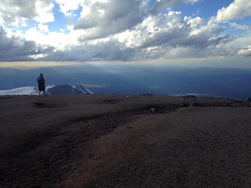 A view of the top of pikes Peak with a guy standing off to the edge