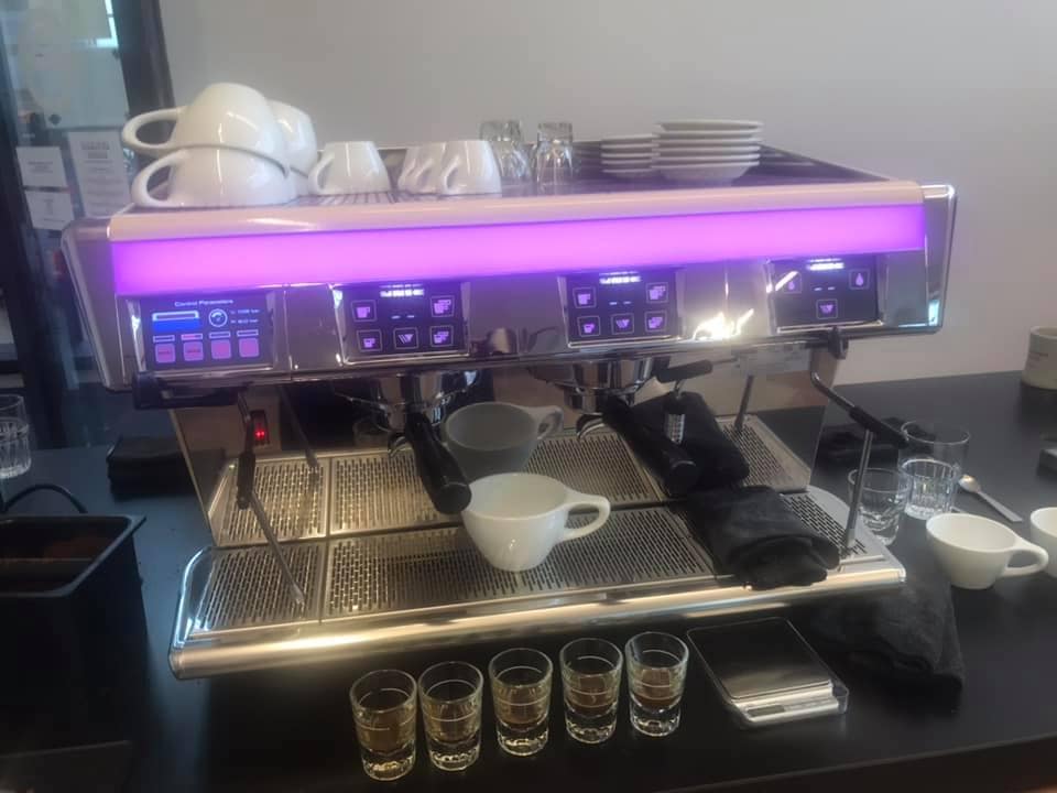 An espresso machine with a pinkish-purple light