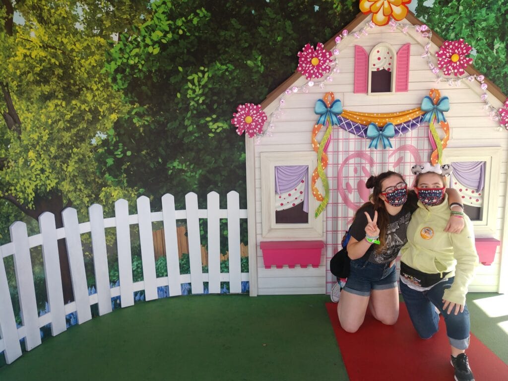 Two girls throwing peace signs in front of Fancy nancy's house at Hollywood Studios