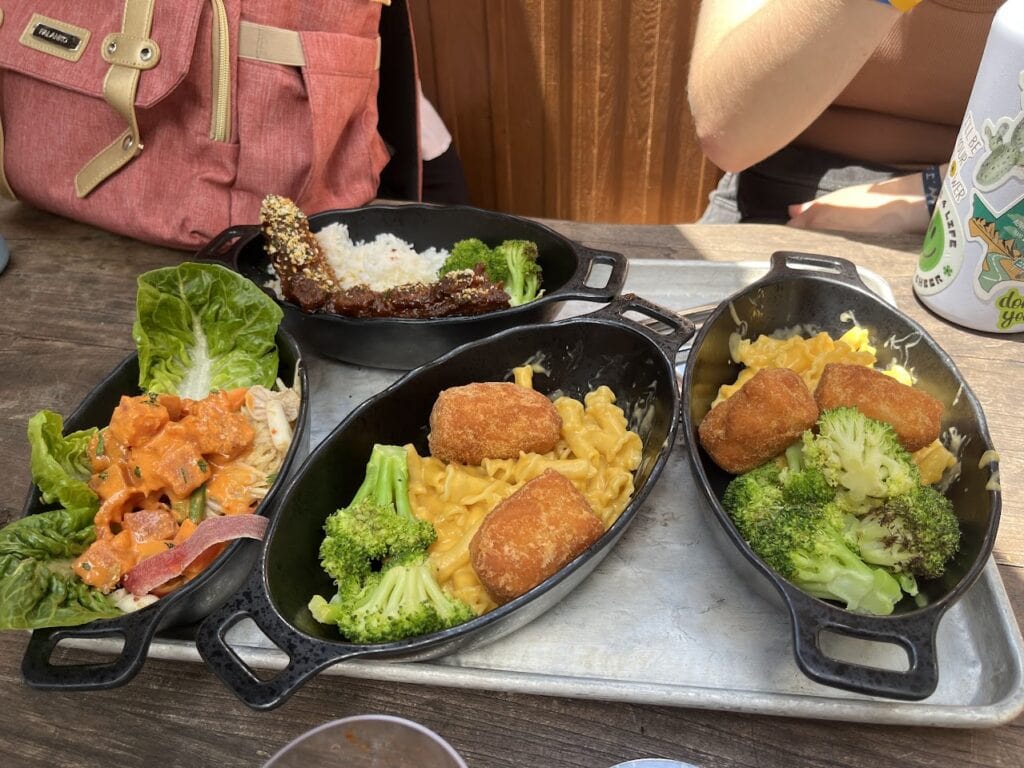 Four different bowls with food in them and a girl's elbow