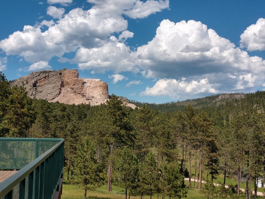 A Far Away view of the Crazy Horse Monument with trees in the foreground