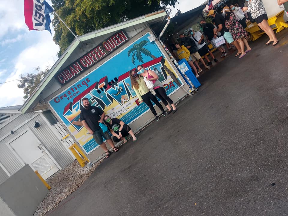 A family of four in front of the cuban coffee queen sign It's crooked so hard to look at