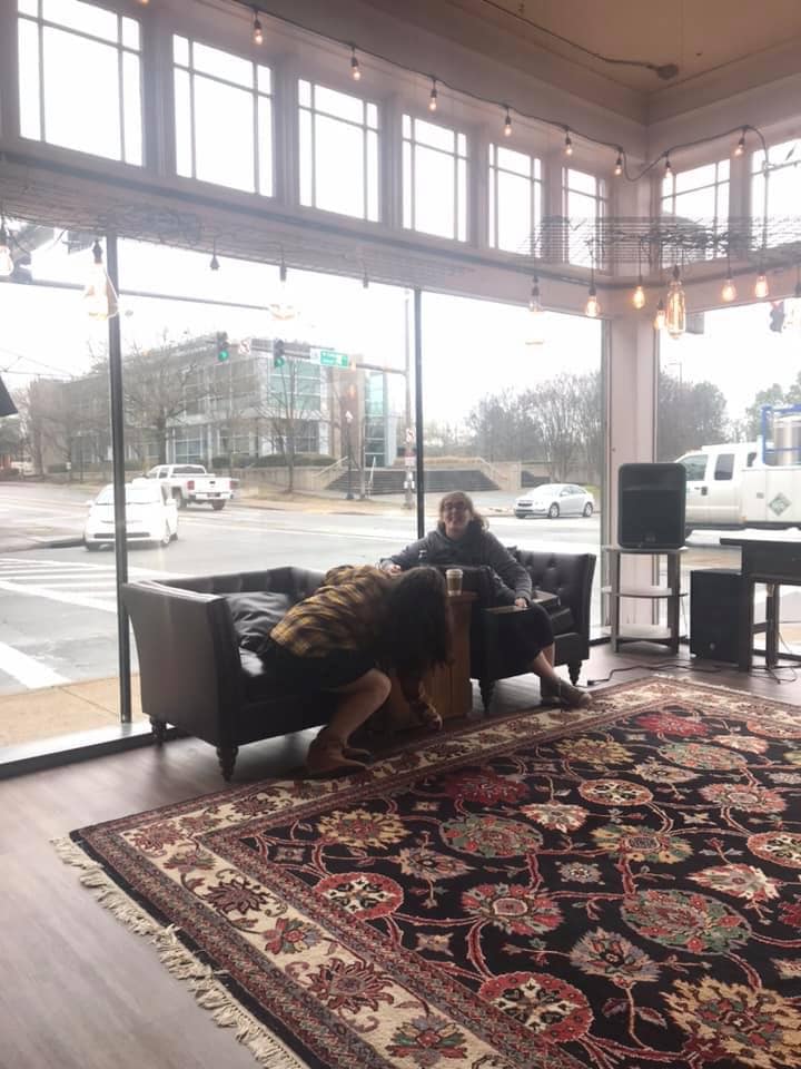 Two girls sitting in a big open space with lots of windows