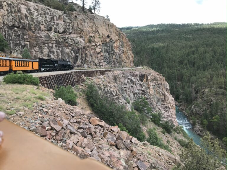 A view of the train's engine area alongside the mountain with the river below