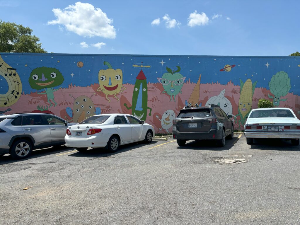 Four cars with a mural that has veggies on it behind them