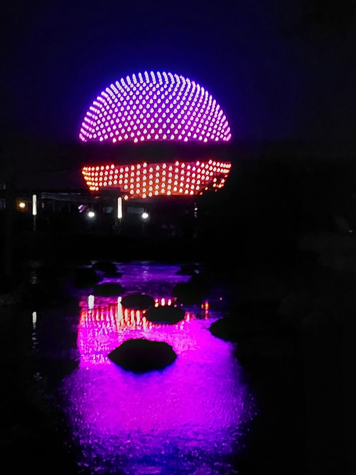 Spaceship Earth lit up in pink and orange at night