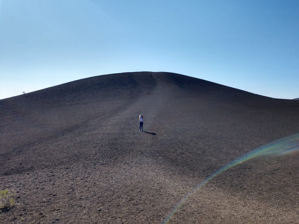 A girl halfway up a lava hill with crystal clear skys above