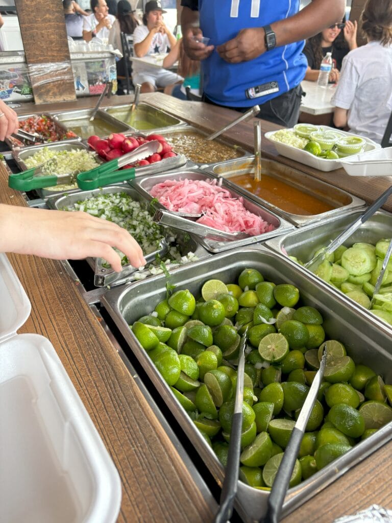 A condiment station for tacos with limes, onions, cilantro and more.