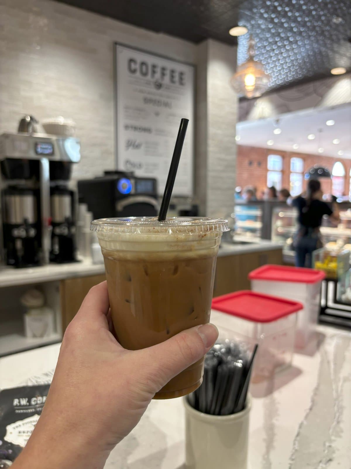 A cold coffee cup being held up in front of The Pioneer Woman Merchantile's coffee shop