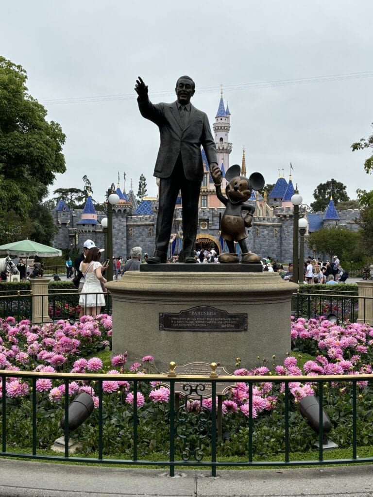 A statue of Walt Disney and Mickey Mouse in front of the Castle at Disneyland